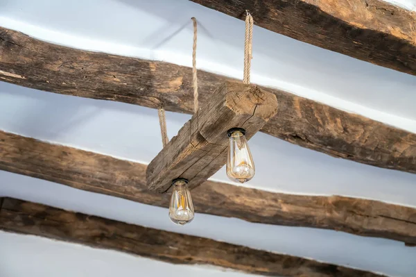 用绳子和老木制成的灯挂在有200年历史的木梁的旧天花板上的低角度照片 — 图库照片