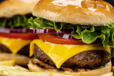 Bir çift lezzetli ev yapımı sığır burger ve siyah tabakta patates kızartması.