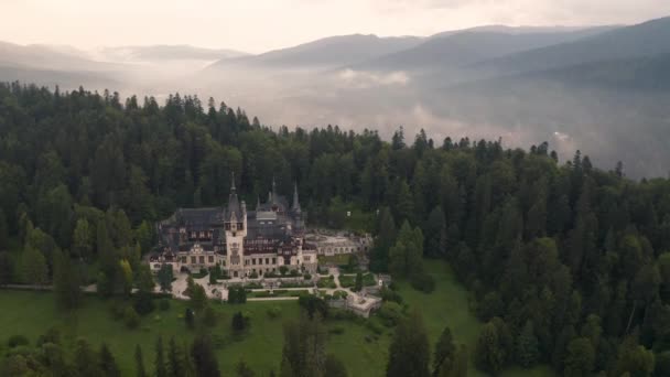 美しいペレス城とその周辺霧深い森の上のドローン飛行と素晴らしいビデオシナイア ルーマニア — ストック動画