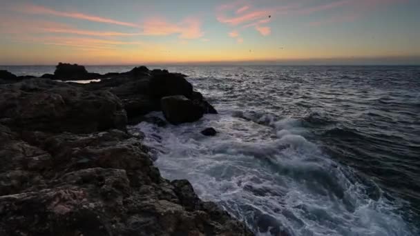 太陽が昇る素晴らしいビデオ 海の波と美しい岩の海岸 — ストック動画