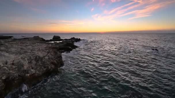太陽が昇る素晴らしいビデオ 海の波と美しい岩の海岸 — ストック動画