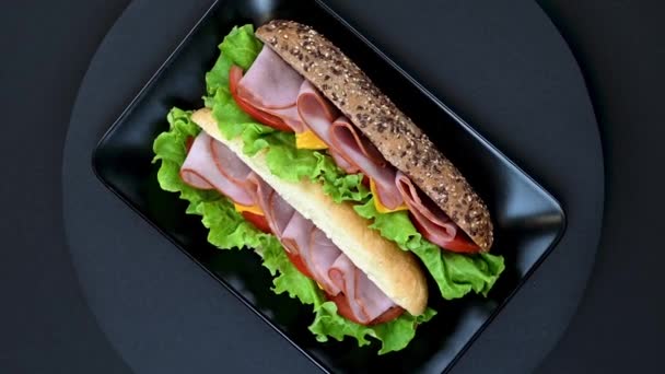 Video Sabrosos Sándwiches Con Jamón Queso Derretido Verduras Plato Negro — Vídeos de Stock
