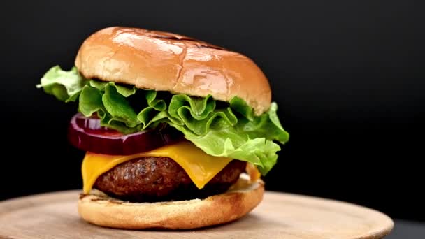 暗い背景でカメラの前で回転する新鮮な食材を使ったおいしい自家製ビーフバーガー クローズアップビュー — ストック動画