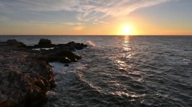 Amazing video with the sun rising, sea waves and a beautiful rocky coast. Slow motion.