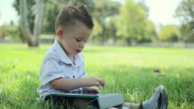 Genç şirin bebek çocuk parkında telefon dokunmatik ekran kullanma.