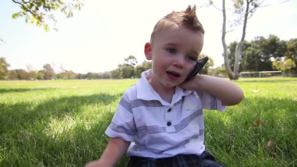 Jonge schattige babyjongen met behulp van touchscreen telefoon op park. — Stockvideo