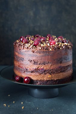 Gri arka planda kirazlı taze yapılmış lezzetli bir çikolatalı pasta. Doğum günü pastası. Boşluğu kopyala.