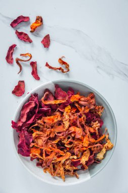 Bir kase sağlıklı sebze cipsi ve parlak bir arka plan. Pancar, havuç, maydanoz ve kereviz sağlıklı bir atıştırmalıktır. Yukarıdan bak. tekst üzerinde yer.