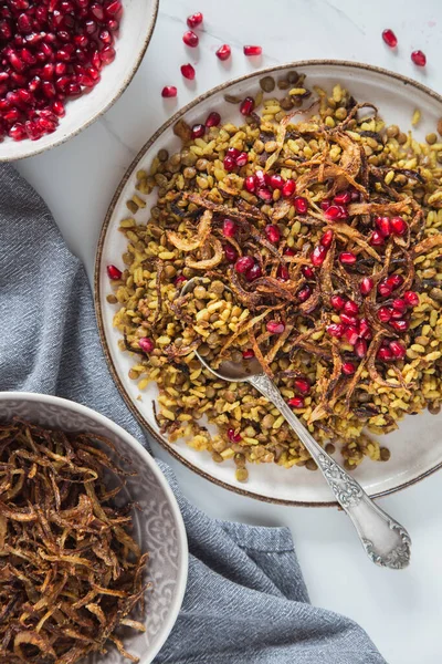 Mujaddara (majadra, mejadra, moujadara, mudardara ve megadarra) pirinç ve nar ile süslenmiş kızarmış soğan. Vejetaryen sağlıklı yemek.