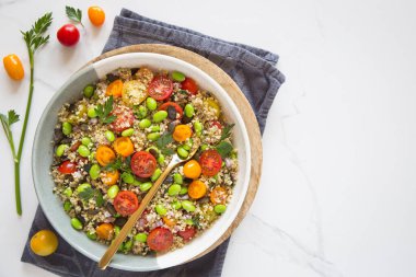 Domatesli kinoa tabbouleh, edamame, kırmızı soğan, maydanoz ve kabak çekirdeği. Sağlıklı bir vejetaryen yemek kasesi.