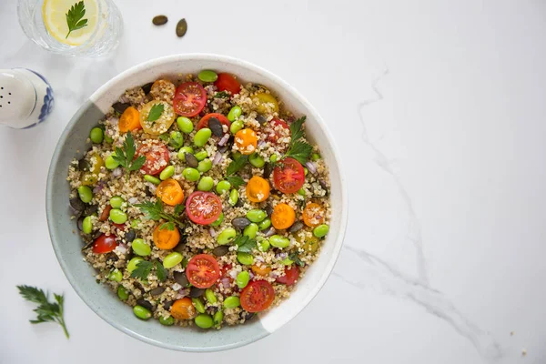 Domatesli kinoa tabbouleh, edamame, kırmızı soğan, maydanoz ve kabak çekirdeği. Sağlıklı bir vejetaryen yemek kasesi.