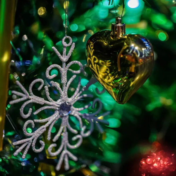 Coração brilhante e floco de neve em um ramo de uma árvore de Natal. Feliz Ano Novo, postal escuro. Profundidade de campo rasa. Imagem escura tonificada — Fotografia de Stock