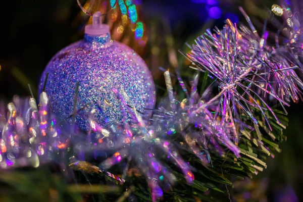 Bola bonita roxa em um pinheiro ou ramo de árvore de Natal. Fundo escuro e guirlanda. Foco suave — Fotografia de Stock