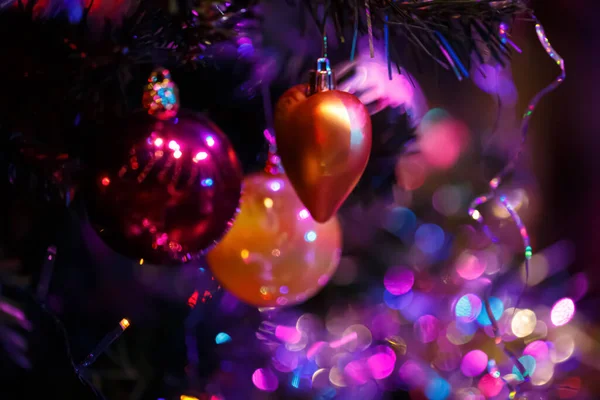 Fundo borrado de coração de brinquedo e bolas em um ramo de uma árvore de Natal. Feliz Ano Novo. Bokeh. Imagem tonificada — Fotografia de Stock