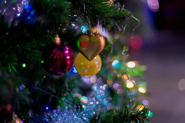 Coração brilhante e bola amarela em um ramo de uma árvore de Natal. Feliz Ano Novo. Profundidade de campo rasa. Bokeh. Imagem tonificada — Fotografia de Stock