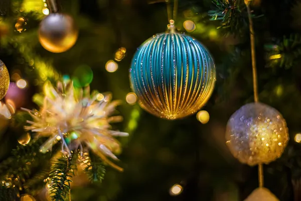 Bolas de Natal em um ramo de um pinheiro e um fundo escuro borrado com bokeh colorido. Foco suave. Espaço de cópia. — Fotografia de Stock