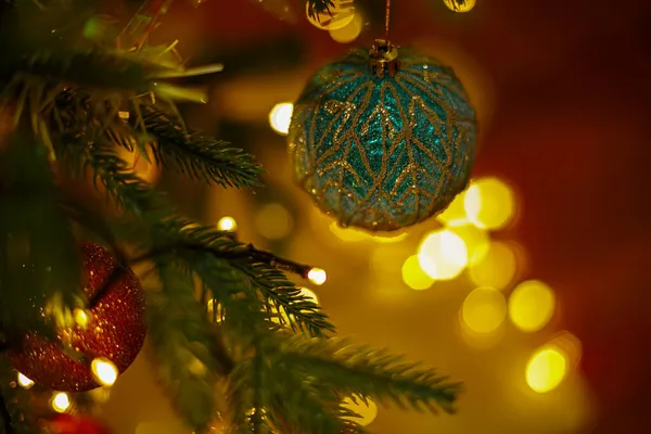 Bolas de Natal em um ramo de um pinheiro e um fundo escuro borrado com bokeh colorido. Foco suave. — Fotografia de Stock