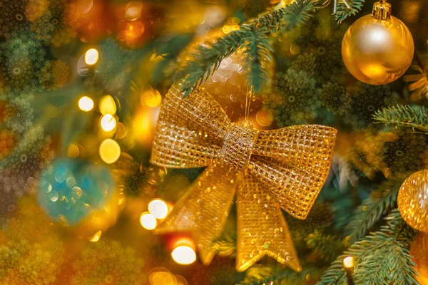 Des boules brillantes et un arc étincelant doré sur le sapin de Noël. Bonne année, carte postale noire. Profondeur de champ faible. Image tonique — Photo