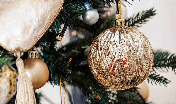 Goldener Festschmuck am Weihnachtsbaum und schöne gelbe Bokeh-Girlanden. — Stockfoto