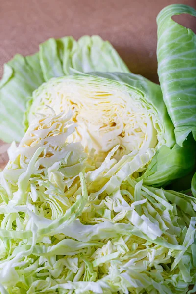 Крупный план нарезанной свежей белой капусты с зелеными листьями. Вегетарианская здоровая вкусная еда. Мелкая глубина резкости. — стоковое фото