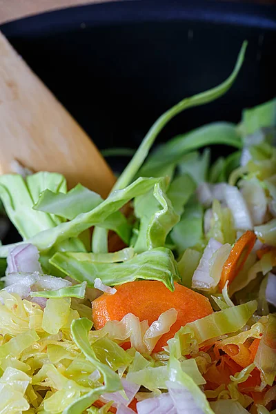 Deliciosa comida saludable. Vista superior de zanahorias fritas con col verde, hierbas y cebollas y una cuchara de madera. Comida vegetariana. —  Fotos de Stock