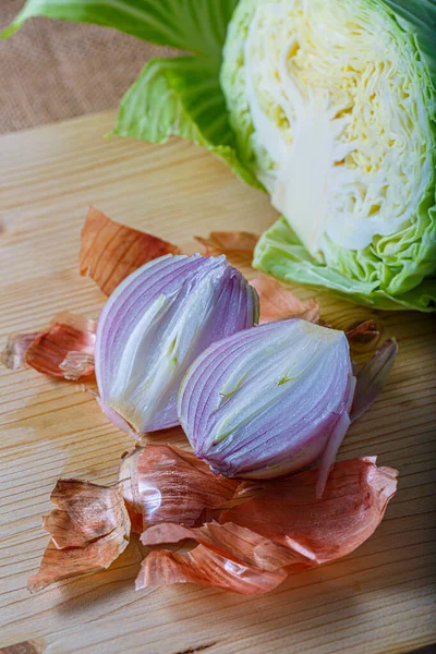 Cebolla morada con cáscara y col blanca en una tabla de madera. Verduras frescas crudas cortadas en dos partes. Enfoque suave. —  Fotos de Stock