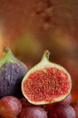 Pembe üzümlere incir kesimi. Meyvelerin sonbahar kompozisyonu ve bulanık arka planda güzel bir bokeh. Sığ alan derinliği