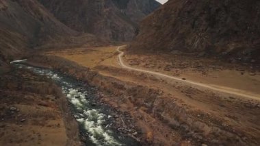 Büyük bir dağ köpüren nehri olan Katu-Yaryk kanyonu Chulyshman Vadisi 'nde boş bir köy yolunda siyah bir SUV aracı sürüyor. Altai, Sibirya, Rusya. İnsanlar kir içinde seyahat eder.
