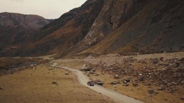 黒いSUVのジープ車は、大きな山の泡の川と巨大なカトゥヤーク峡谷チュリーシュマン渓谷の空の田舎道に沿って運転しています。アルタイ、シベリア、ロシア。土の上を旅する — ストック動画