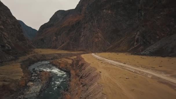 Een zwarte SUV jeep auto rijdt langs een lege landweg in de enorme Katu-Yaryk canyon Chulyshman Valley met een grote berg borrelende rivier. Altai, Siberië, Rusland. Mensen reizen langs een modder. — Stockvideo