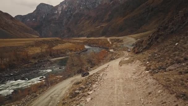 Czarny samochód jeepa SUV jedzie pustą wiejską drogą w ogromnym kanionie Katu-Yaryka Chulyshman Valley z dużą górską rzeką bąbelkową. Altai, Syberia, Rosja. Ludzie podróżują po ziemi. — Wideo stockowe