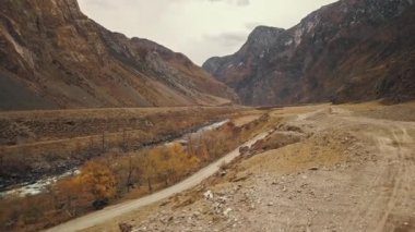 Büyük bir dağ köpüren nehri olan Katu-Yaryk kanyonu Chulyshman Vadisi 'nde boş bir köy yolunda siyah bir SUV aracı sürüyor. Altai, Sibirya, Rusya. İnsanlar kir içinde seyahat eder.