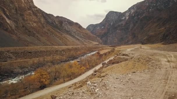 A black SUV jeep car is driving along an empty country road in the huge Katu-Yaryk canyon Chulyshman Valley with a large mountain bubbling river. Altai, Siberia, Russia. People travel along a dirt — Stock Video