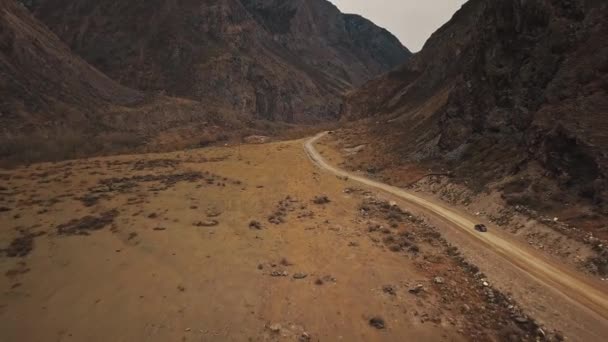一辆黑色的SUV吉普车正沿着一条空旷的乡间公路行驶在巨大的Katu-Yaryk峡谷的Chulyshman山谷中，一条巨大的山体在冒泡。阿尔泰，西伯利亚，俄罗斯人们在泥泞中旅行 — 图库视频影像