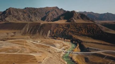Altai Cumhuriyeti, Sibirya, Rusya. Nadir ağaçlar, yeşil nehir Biya ve Katun, uçsuz bucaksız bir tarlada köprüsü ve bozkırı ve arka planda büyük taş dağları olan bir otoyol. Gökyüzü görünümü