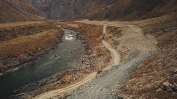 Een zwarte SUV jeep auto rijdt langs een lege landweg in de enorme Katu-Yaryk canyon Chulyshman Valley met een grote berg borrelende rivier. Altai, Siberië, Rusland. Mensen reizen langs een modder. — Stockvideo