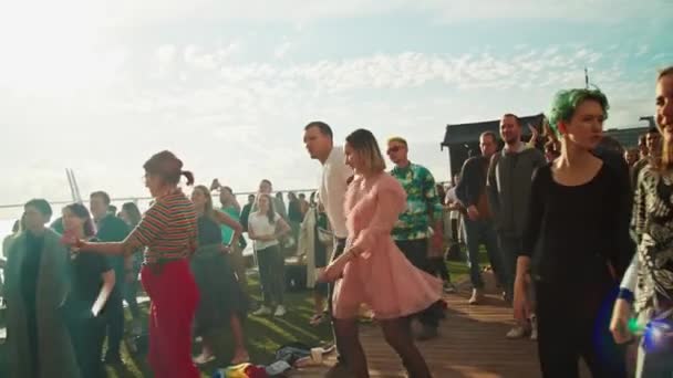 Tłum młodych ludzi, fani tańczący przed sceną, cieszący się muzyką na Letnim Festiwalu Muzycznym Stereoleto, Sankt Petersburg, Sevkabel 2020. Impreza, letnie wibracje, przyjaźń, młodzież — Wideo stockowe