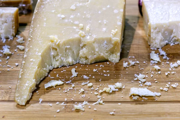 Tahta kesme tahtasının üzerinde duran bir parça baharatlı parmesan peyniri. — Stok fotoğraf