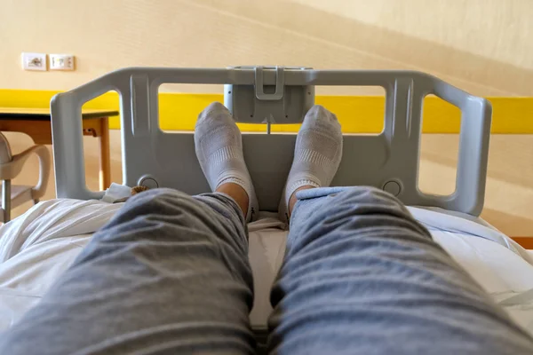 Concept gezondheid en geneeskunde: selfie van voeten met witte sokken van een patiënt zittend in een ziekenhuisbed — Stockfoto