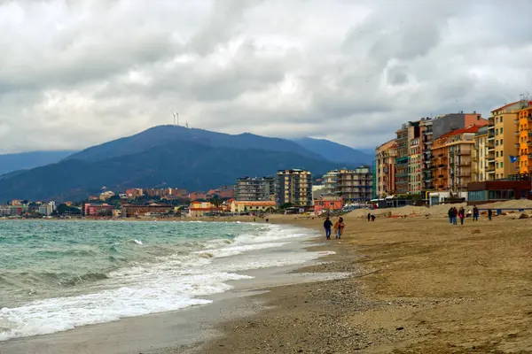 Лигурийское море, Италия: городской пейзаж с точки зрения пляжа с гражданами, идущими зимой — стоковое фото
