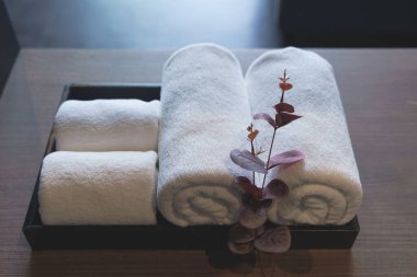 Beyaz yumuşaklık pamuğu ve temiz tekstil katlanmış giysileri ahşap masanın üzerine koyuyor. Modern otel ya da otel odaları için kaplıca ve hijyen ve dekorasyon kavramı çağdaş.