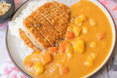 Pirinçli kızarmış domuz pirzolası ve ekmeklenmiş, bol yağda kızartılmış köri soslu lezzetli Japon yemeği. Popüler ulusal basit yiyecek kavramını kabul et.