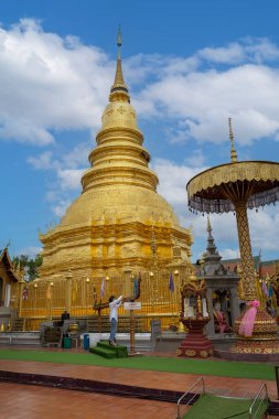 Lamphun, Tayland - 22 Mart 2022: Wat Phra 'daki antik güzel Altın Pagoda Hariphunchai tapınağı Lamphun, Kuzey Tayland' da mavi gökyüzü ile turistler arasında en popüler yer..