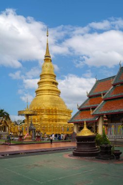 Lamphun, Tayland - 22 Mart 2022: Wat Phra 'daki antik güzel Altın Pagoda Hariphunchai tapınağı Lamphun, Kuzey Tayland' da mavi gökyüzü ile turistler arasında en popüler yer..