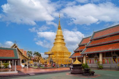Lamphun, Thailand - March 22, 2022: Ancient beautiful Golden Pagoda at Wat Phra That Hariphunchai temple is the most famous place popular among tourists with blue sky in Lamphun, Northern Thailand.