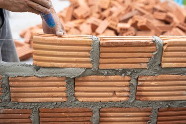 Construction worker installing bricks masonry bricklayer and adjusting bricks walls using trowel, mortar and putty knife. Concept construction work in the countryside building.