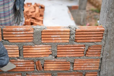 İnşaat işçisi tuğla ustası, tuğla ustası ve tuğla duvarları mala, havan topu ve macun bıçağıyla düzenliyor. Kırsal binalarda konsept inşaat işi.