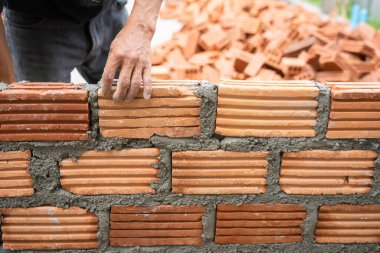 İnşaat işçisi tuğla ustası, tuğla ustası ve tuğla duvarları mala, havan topu ve macun bıçağıyla düzenliyor. Kırsal binalarda konsept inşaat işi.