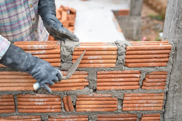 Construction worker installing bricks masonry bricklayer and adjusting bricks walls using trowel, mortar and putty knife. Concept construction work in the countryside building.