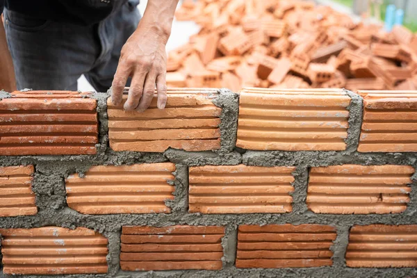 İnşaat işçisi tuğla ustası, tuğla ustası ve tuğla duvarları mala, havan topu ve macun bıçağıyla düzenliyor. Kırsal binalarda konsept inşaat işi.